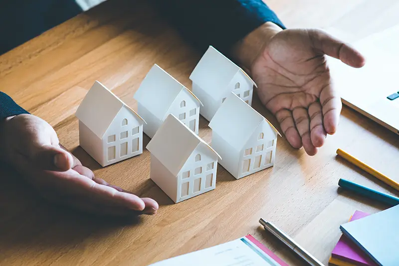 Realtors hands displaying paper model houses